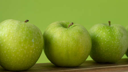 Green and fresh apples on wooden background and on green colorの写真素材