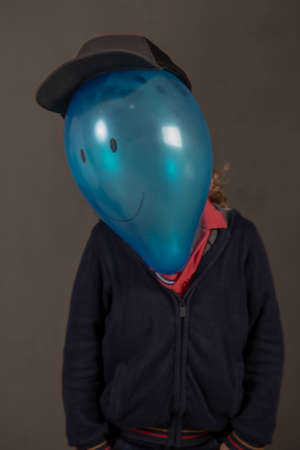 Painted blue balloon head with a happy face on a child's bodyの写真素材