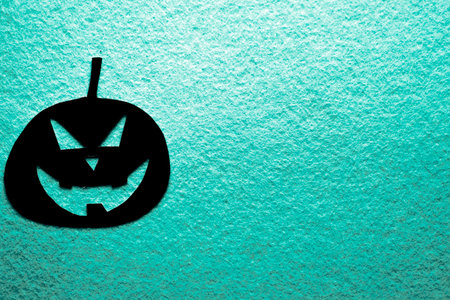 Cut-out paper pumpkin painted black on colored backgroundの写真素材