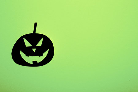 Cut-out paper pumpkin painted black on colored backgroundの写真素材