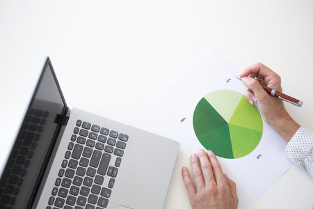 Paper with green statistical pie chart. Detail of a hand checking some mathematical graphsの写真素材