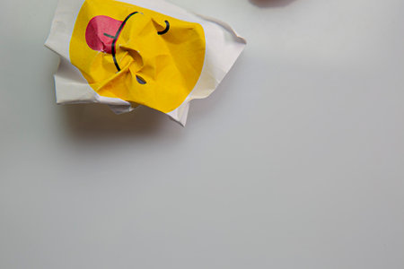 Square piece of paper with the face of a mocking emoji with tongue out.