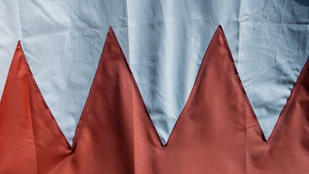 Photograph of two triangles of red cloth sewn on a white canvas.の写真素材