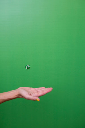 Woman's hand with outstretched palm throwing a die in the airの写真素材