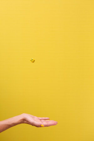 Woman's hand with outstretched palm throwing a die in the airの写真素材