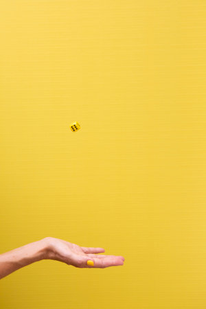 Woman's hand with outstretched palm throwing a die in the airの写真素材