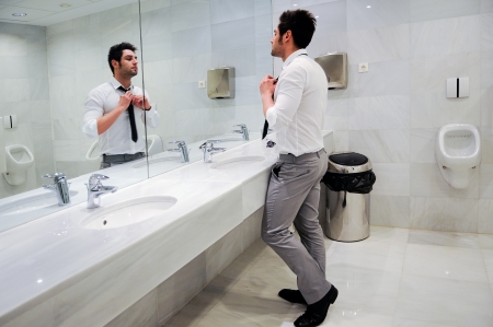 Man getting dressed in a public restroom with mirrorの写真素材