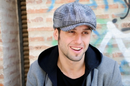 Portrait of handsome man in urban background wearing a retro cap and smiling