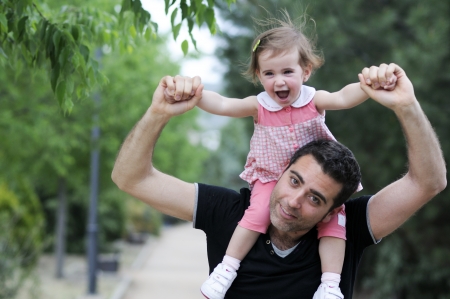 Little girl walking on the shoulders of her father in the park