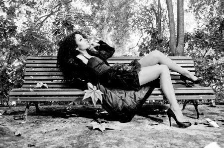 Young beautiful woman siting on bench in parkの写真素材