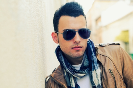 Portrait of a young handsome man, model of fashion, wearing tinted sunglasses in urban backgroundの写真素材