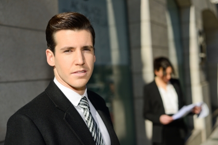 Portrait of attractive young businessman in the city with beautiful businesswoman in the backgroundの写真素材