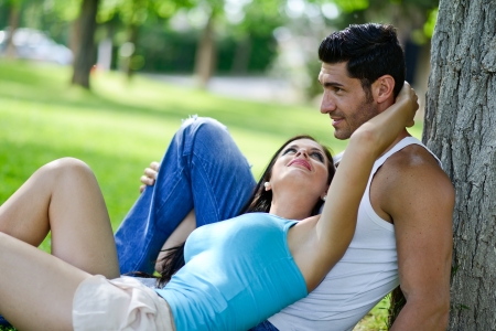 Happy smiling couple laying on green grass in a beautiful parkの写真素材