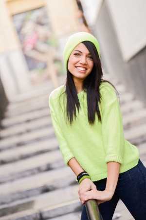 Portrait of brunette young woman with green eyes, wearing green casual clothes and hat, in urban backgroundの写真素材