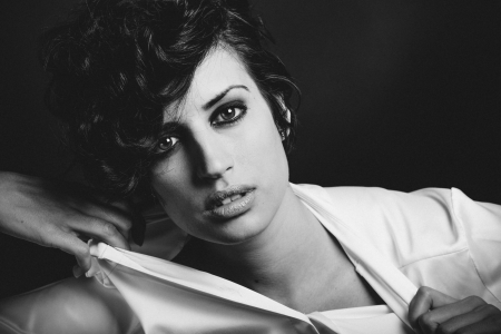 Portrait of woman with intense look on black background, bared shoulder. Studio portraitの写真素材