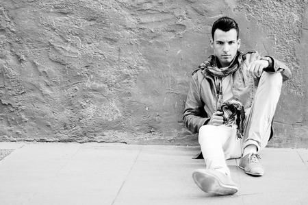 Portrait of a young attractive man sitting on the floor of the streetの写真素材