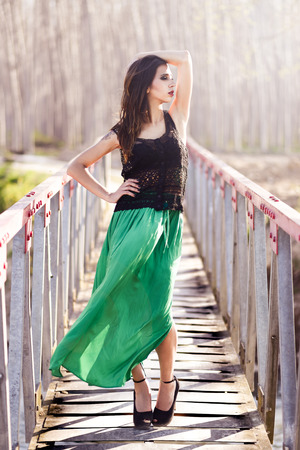 Portrait of beautiful young woman wearing long dress in a rural bridgeの写真素材