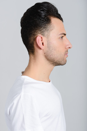 Portrait of a smart serious young man standing against white background の写真素材