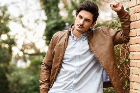 Portrait of a young handsome man, model of fashion, with modern hairstyle in urban background,...