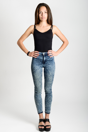 Young woman wearing black tank top and blue jeans on white background.  Studio shotの素材 [FY31052017365] | ストックフォトのamanaimages PLUS