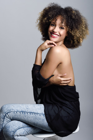 Young black woman with afro hairstyle laughing. Girl wearing black clothes. Studio shot.の写真素材