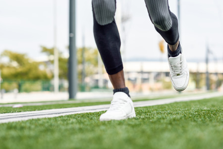 Feet of black man starting running in urban background. Male doing workout outdoors.の写真素材