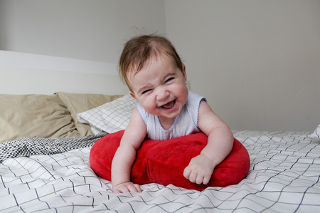 Smiling baby girl lying on her parents bed with funny expressionの写真素材