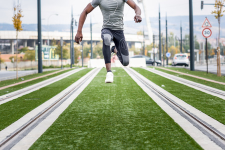 Black man jumping in urban background. Male doing workout in the street.