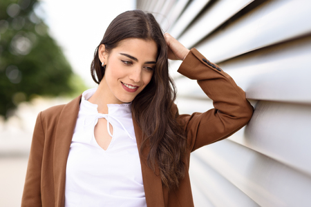 Young woman with nice wavy long hair. Beautiful girl wearing formal wear. Young female with brown jacket.の写真素材