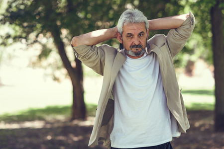 Portrait of a mature man, model of fashion, in an urban park. Senior male with white hair and beard wearing casual clothes.の写真素材