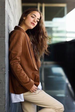 Young woman with nice wavy long hair. Beautiful girl wearing formal wear. Young female with brown jacket.の写真素材