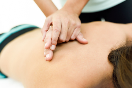 Young woman receiving a back massage in a spa center. Female patient is receiving treatment by professional therapist.の写真素材