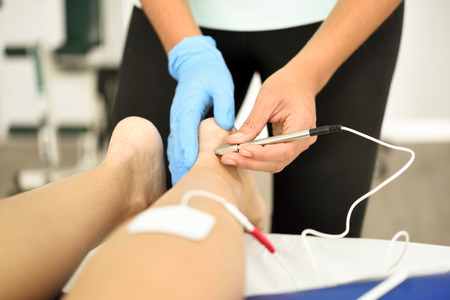 Electroacupuncture dry with needle connecting machine used by acupunturist on female patient for...