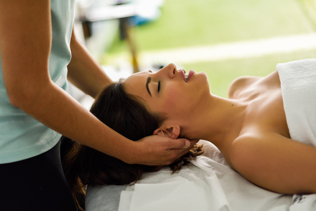 Young caucasian smiling woman receiving a head massage in a spa center with eyes closed. Female patient is receiving treatment by professional therapist.の写真素材