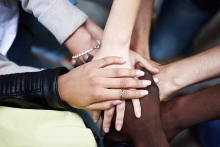 Close up top view of young people putting their hands together. Friends with stack of hands showing unity and teamwork.の写真素材