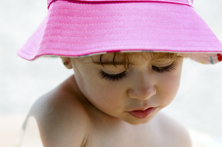 Close-up potrait of adorable little girl outdoors wearing sun hat.の写真素材