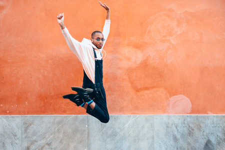 Young black man wearing casual clothes jumping in urban background. Lifestyle concept. Millennial...