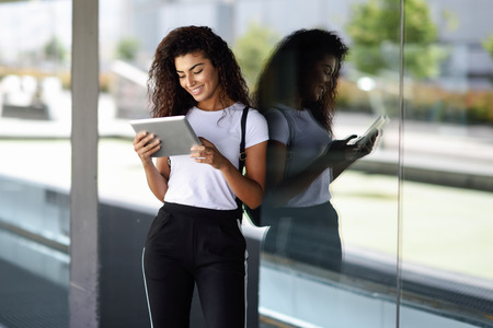 Happy young Arab woman using digital tablet in business background. Happy girl wearing sportswear.