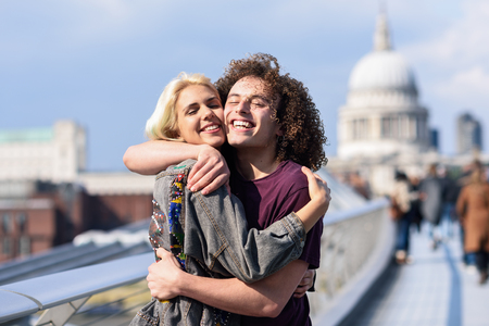 Happy couple hugging by Millennium bridge, River Thames, London.の写真素材