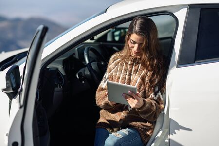 Young traveler woman using digital computer in snowy mountains in winter.