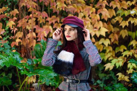 Young beautiful girl with very long hair wearing winter coat and cap in autumn leaves backgroundの写真素材