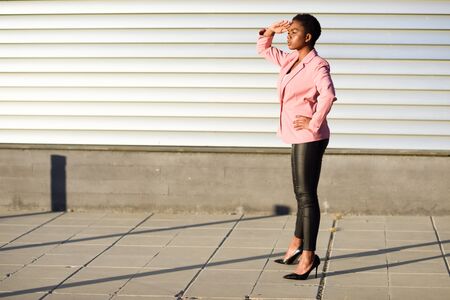 Black woman, model of fashion, standing on urban wallの写真素材