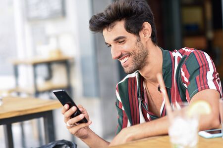 Young man using smartphone in an urban cafe.
