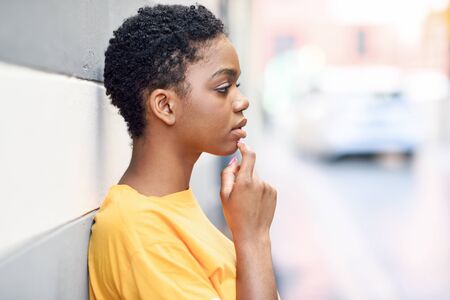 Thoughtful black woman with sad expression outdoors.の写真素材