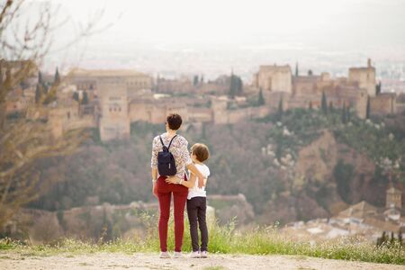 Mother and little daughter looking at the Alhambra of Granada from Cerro de San Miguel. Single parent family doing tourism.の写真素材