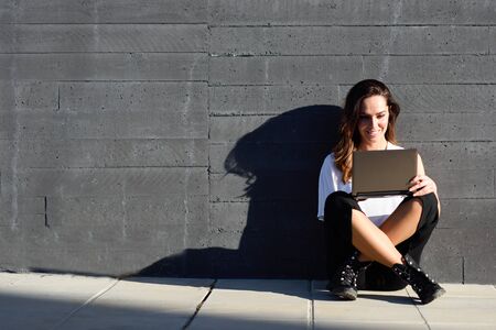 Young businesswoman working with her laptop computer sitting on the floor.