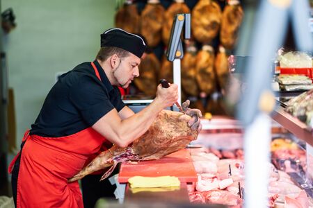 Butcher boning a ham in a modern butcher shopの写真素材