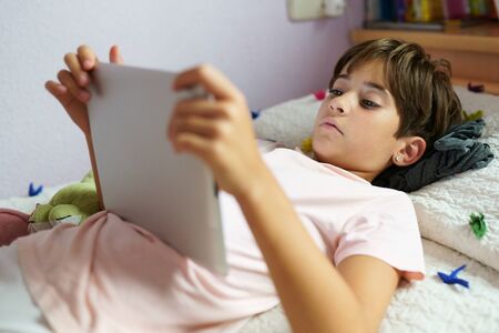 Cute girl using a tablet computer in her bedroom