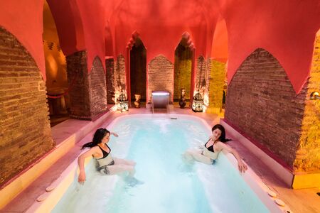 Two women enjoying Arabic baths Hammam in Granada, Andalusia, Spain. Elvira baths. Hot water pool.