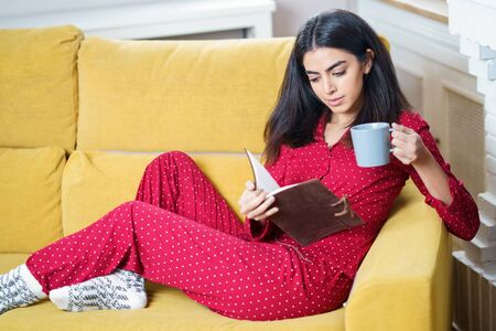 Woman at home having tea and readingの写真素材